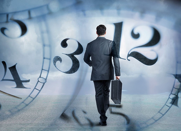 時計の前に立つビジネスマン